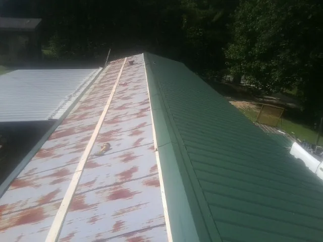 Old rusted panels beside newly installed green metal roofing — Wind Damage Roof Repair by Roofing Brothers in Overland Park