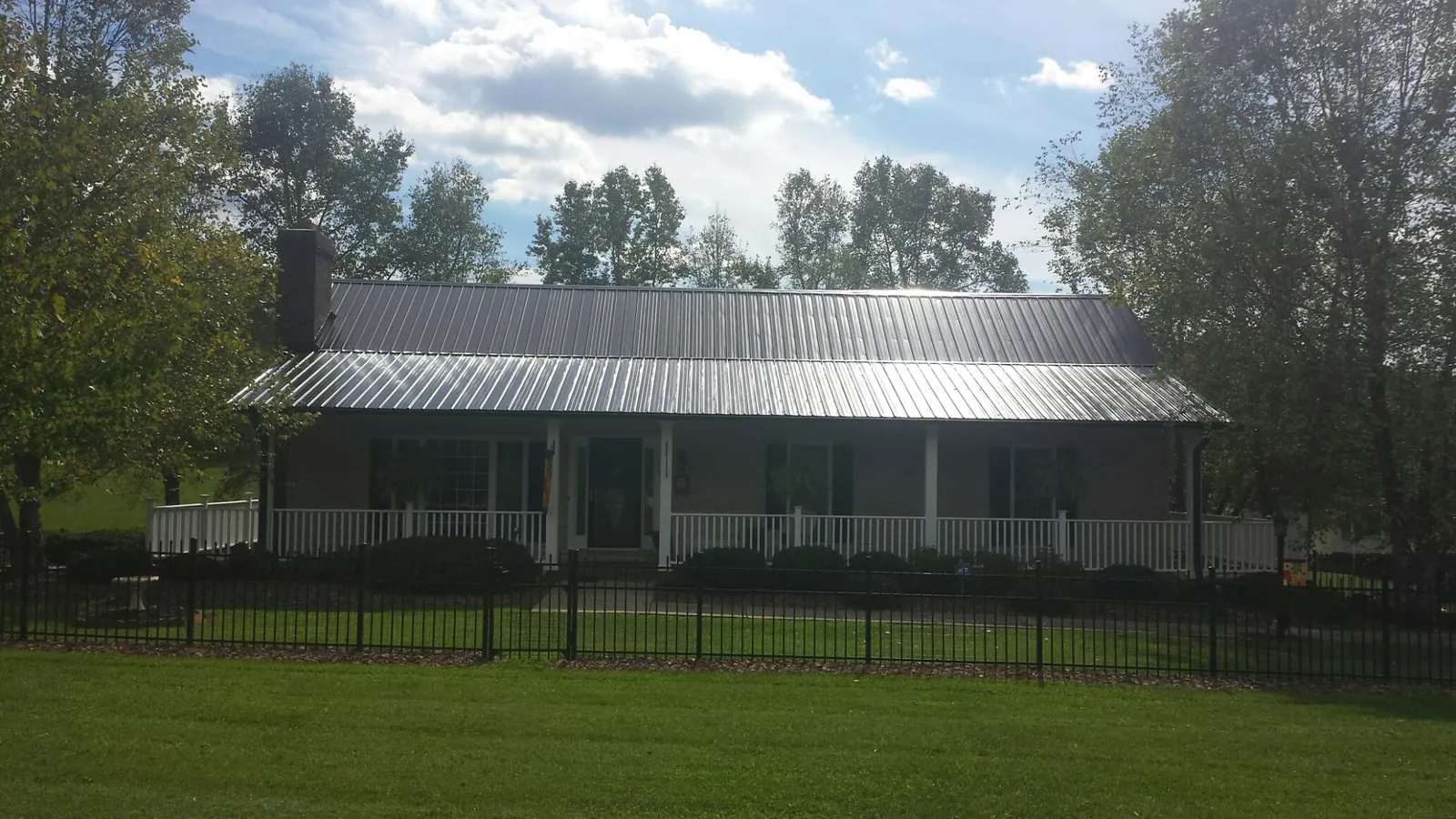 Gray metal roof on a brick ranch with a full width front porch — Gutter Guard Installation work by our crew in Overland Park