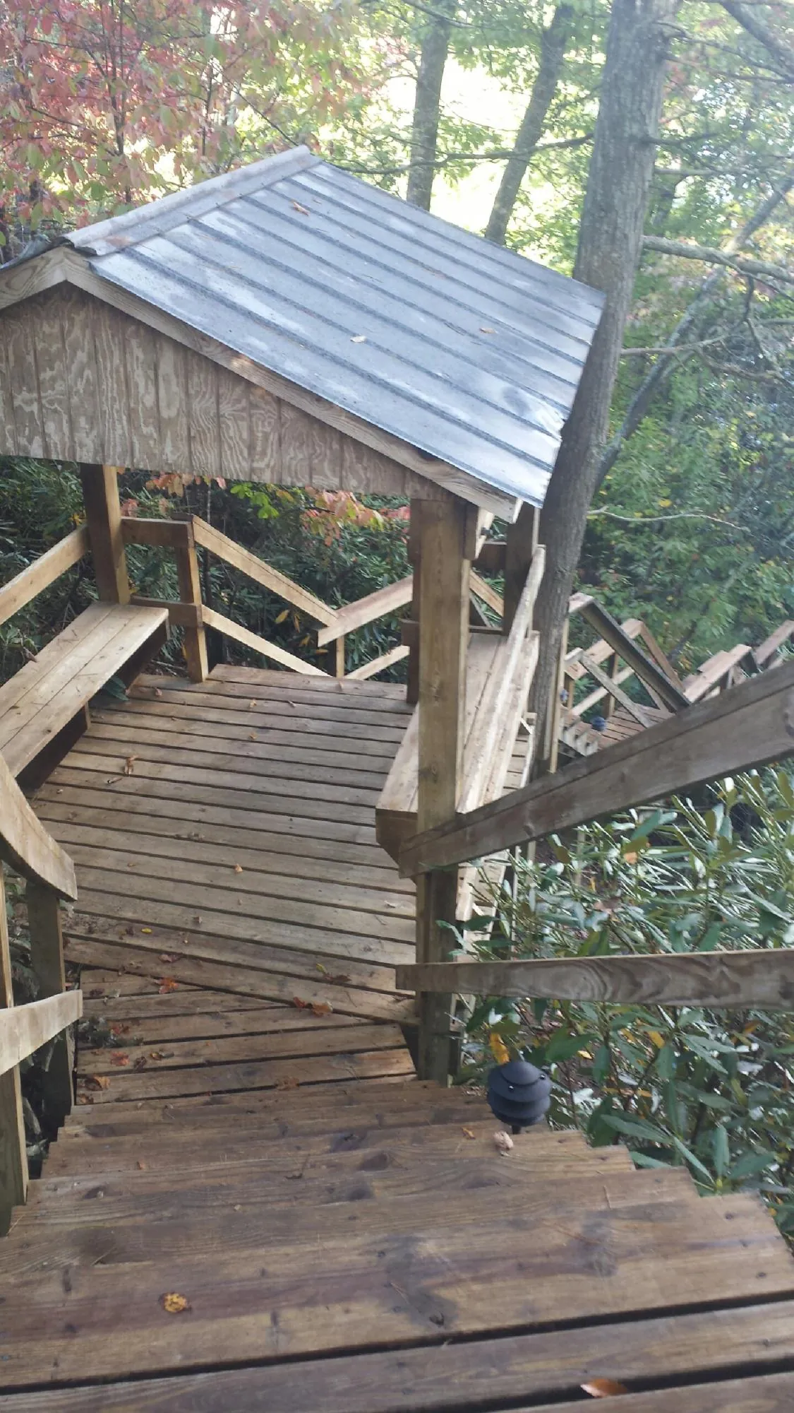 Metal roofed shelter over wooden steps on a wooded walkway — Skylight Repair & Installation work by our crew in Overland Park