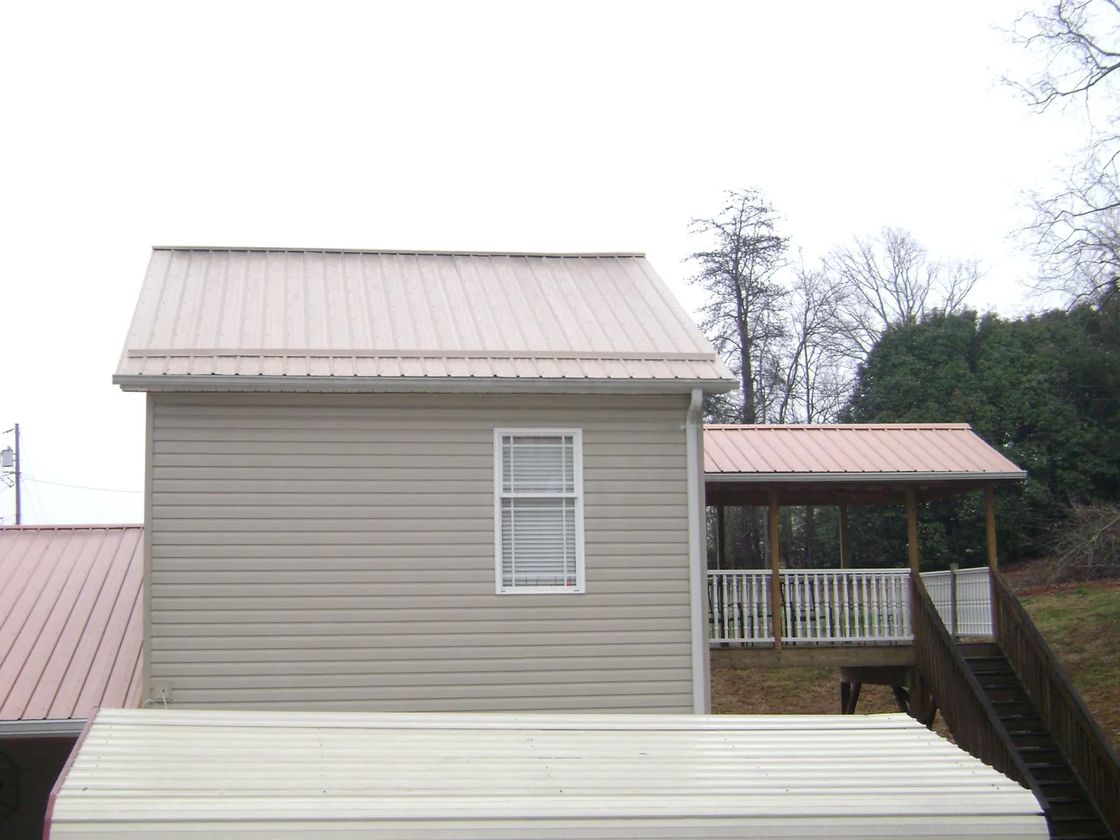 Tan metal roofs on a two story addition and attached porch, from a Roof Replacement job in Overland Park