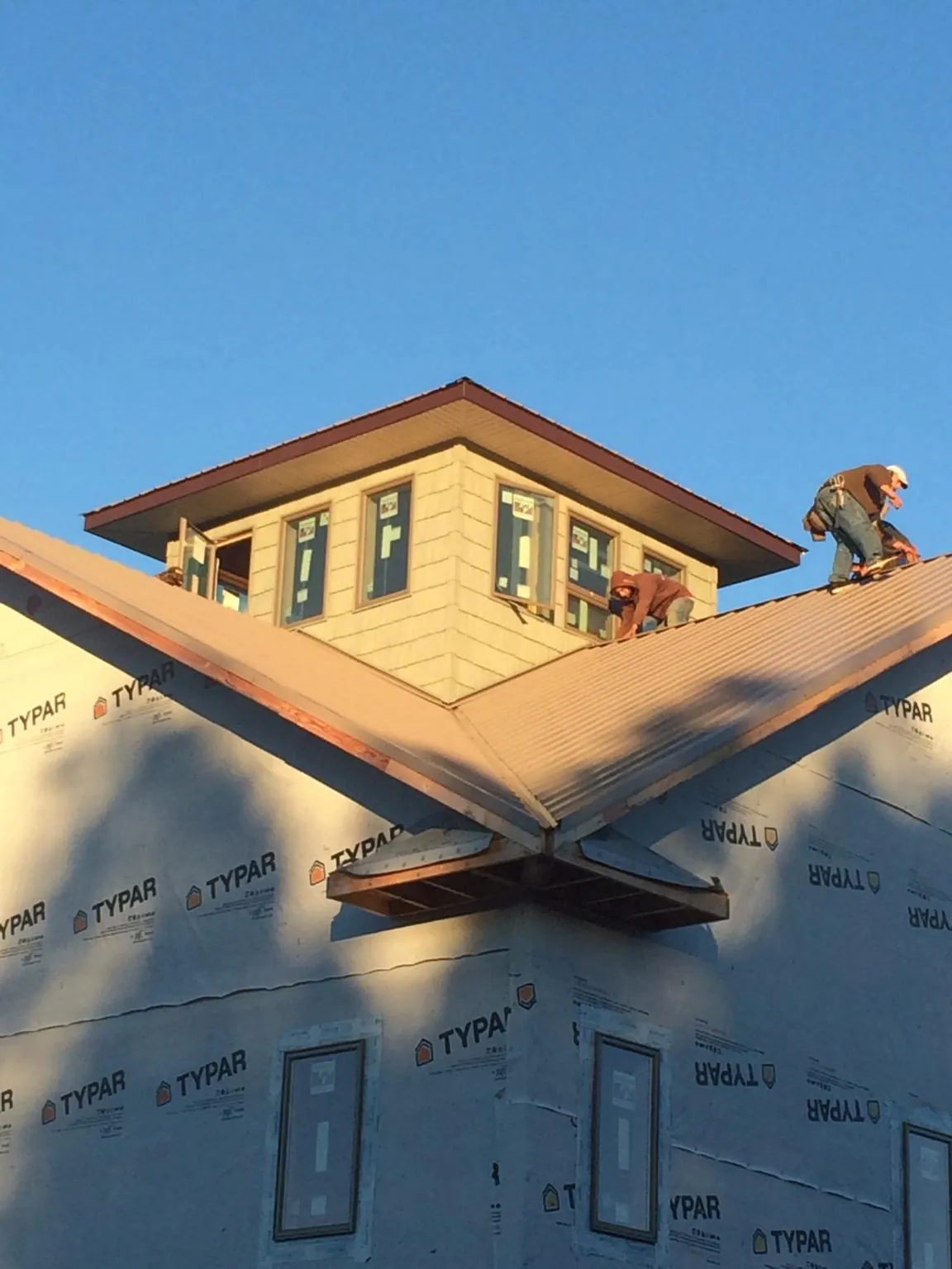 Roofers working around a rooftop cupola on a new metal roof at sunset — Roof Waterproofing in Overland Park by Roofing Brothers